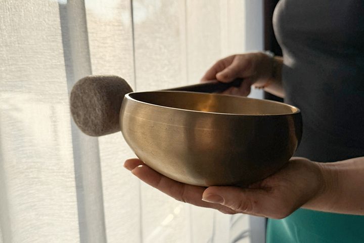 Sound-Healing - schöne Klangschale Eine Frau steht vor einem Fenster und hält eine schöne Klangschale in der Hand.